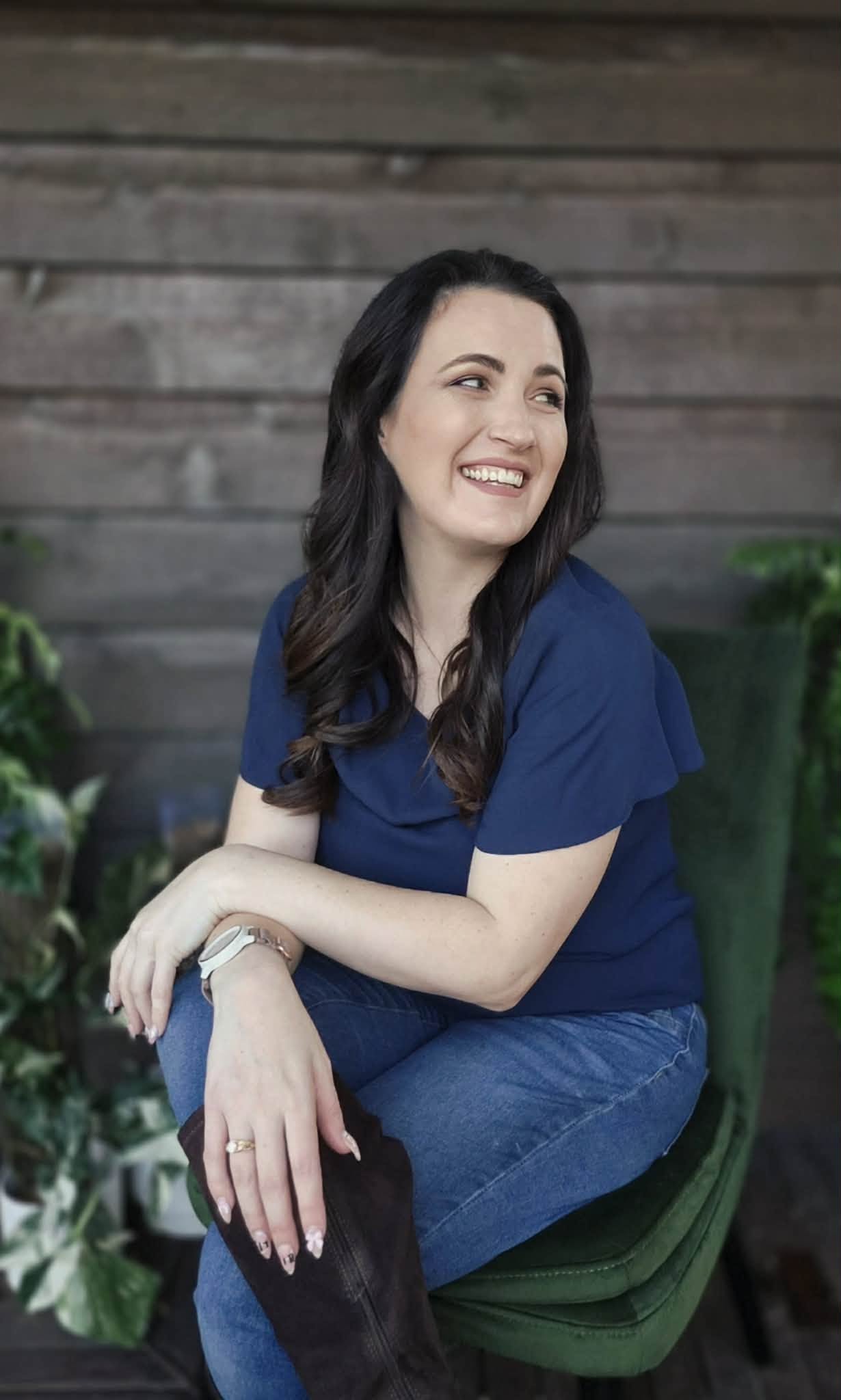 Cassandra Penfold, founder of Ulysses Interiors, smiling among ferns