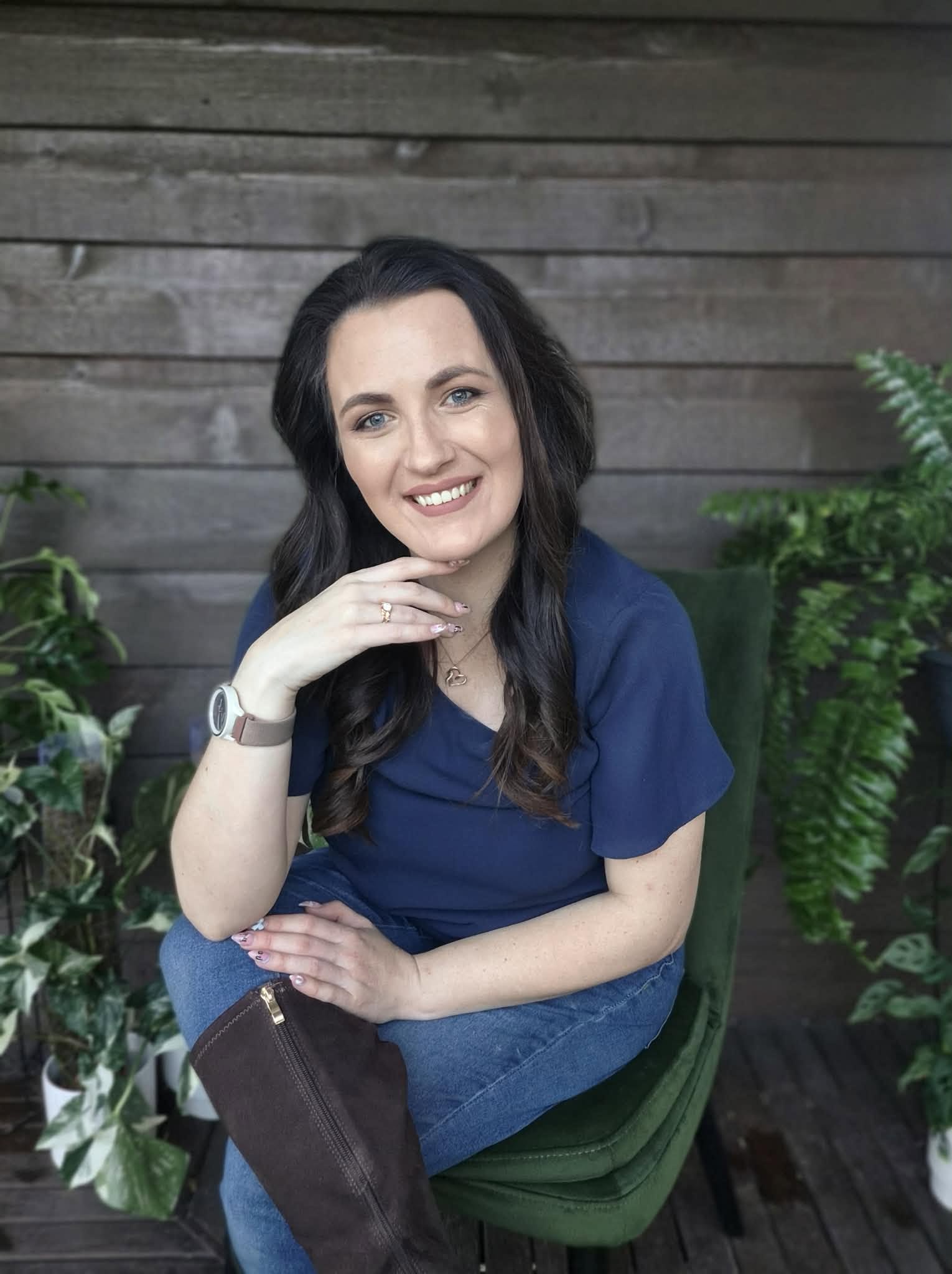 Cassandra Penfold, founder of Ulysses Interiors, seated and smiling among ferns
