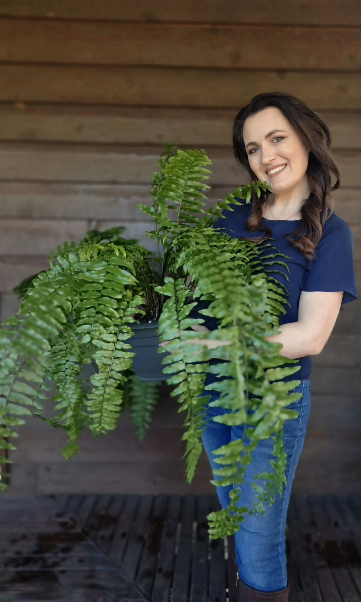 Cassandra Penfold laughing, seated among plants on her studio's back porch